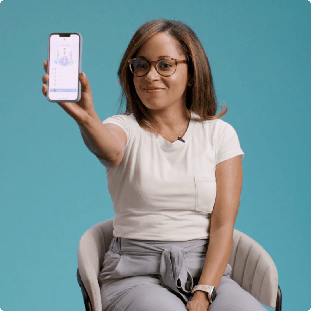 An employee sitting in a chair showing her phone and position in the leaderboard in the YuLife app.