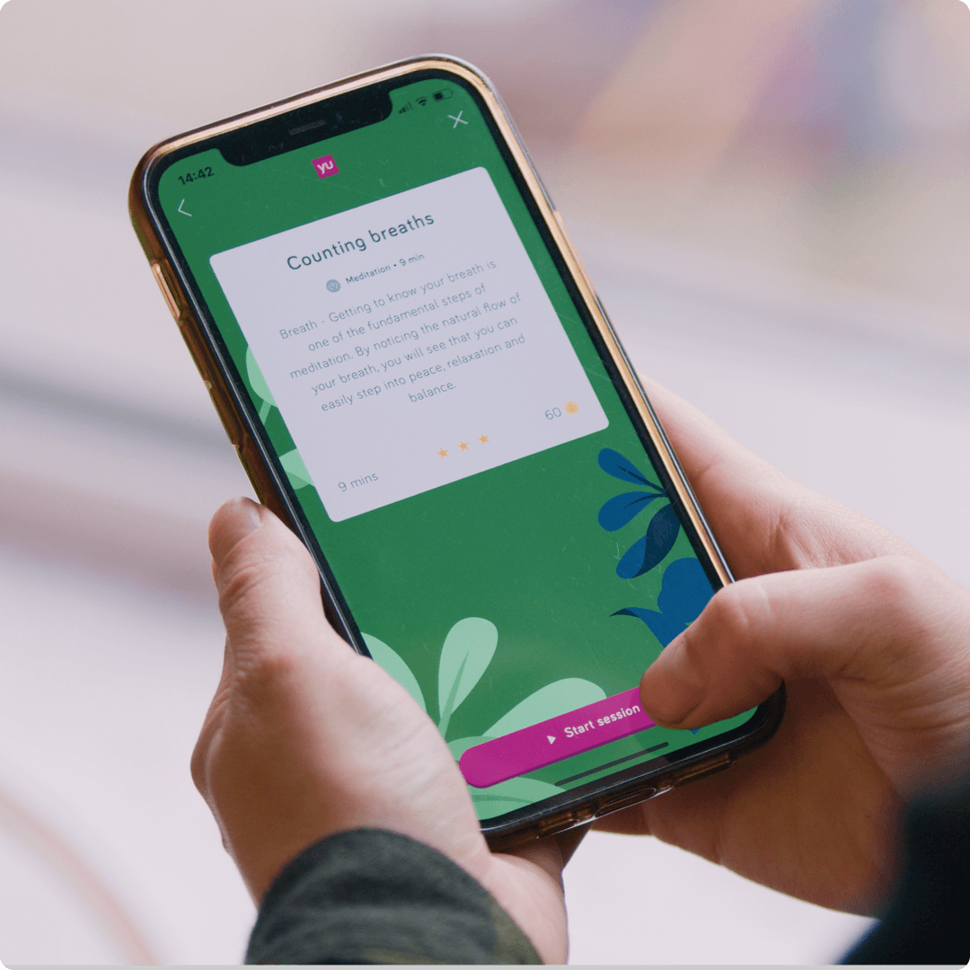 A user holding an iPhone about to start a meditation in the YuLife app. 